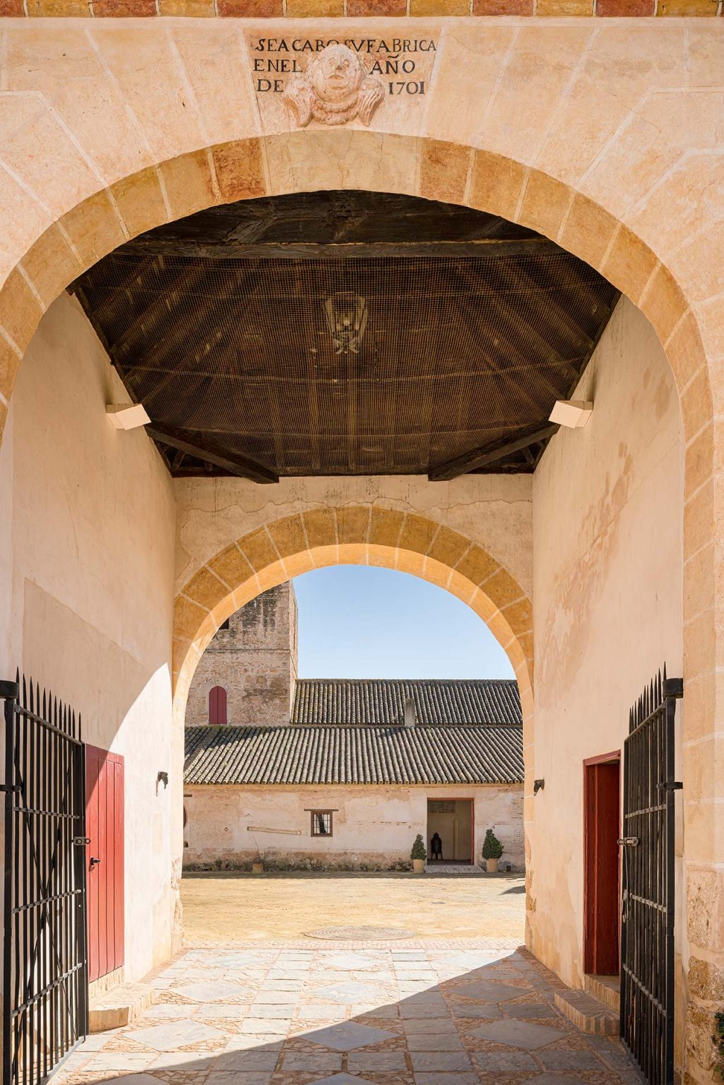 Zaguán con arcos de piedra y techo de madera abierto al patio de la hacienda