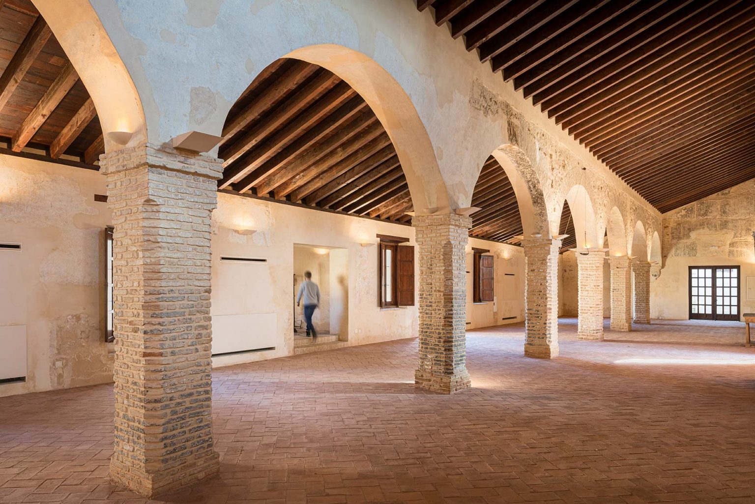 Nave con arcos de ladrillo, techo de vigas de madera y solería de barro