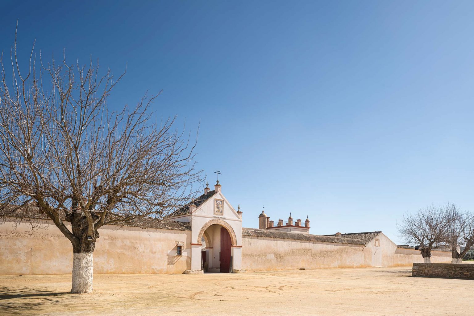 Portada con arco y espadaña de la Hacienda La Soledad, con árboles desnudos