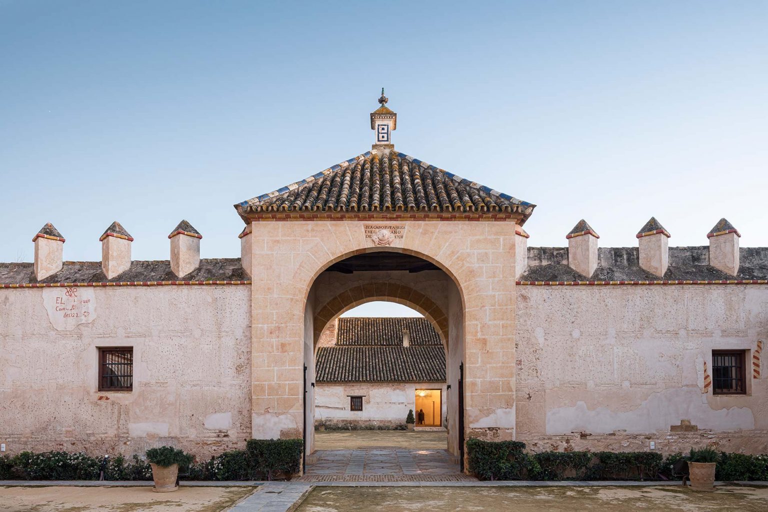 Arco de acceso a la hacienda, con el muro almenado y el patio al fondo