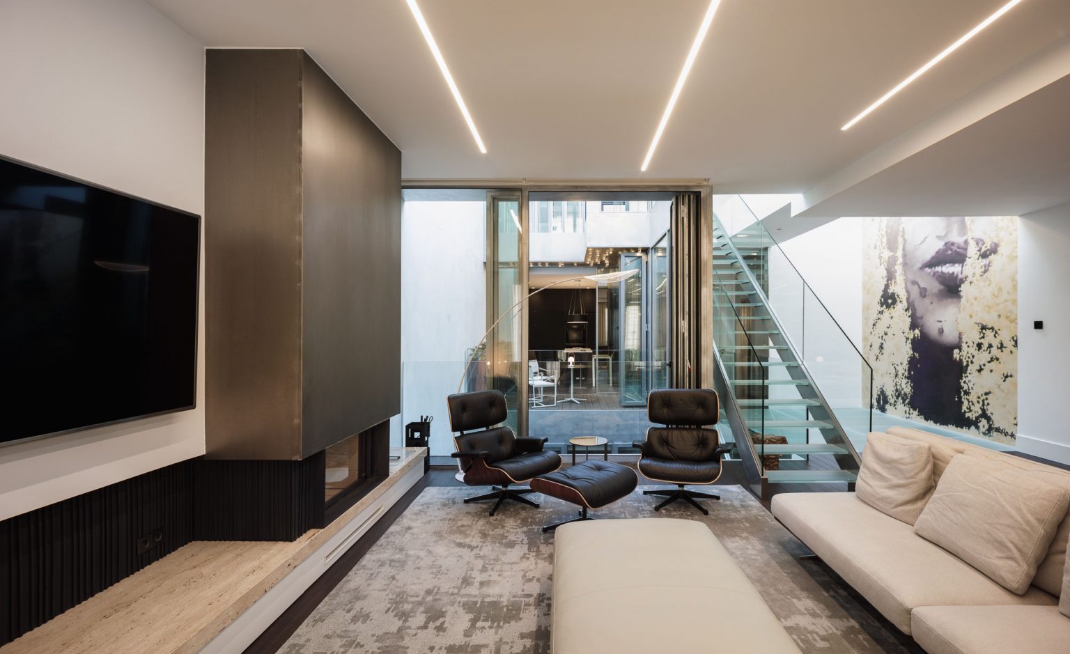Salón con panel de madera y escalera acristalada al fondo, en la Casa en Triana