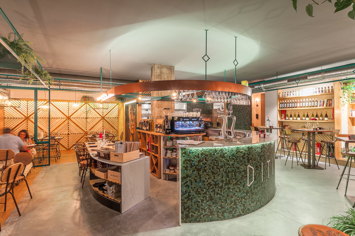 Sala del restaurante con mesas alrededor de la barra curva de mosaico verde