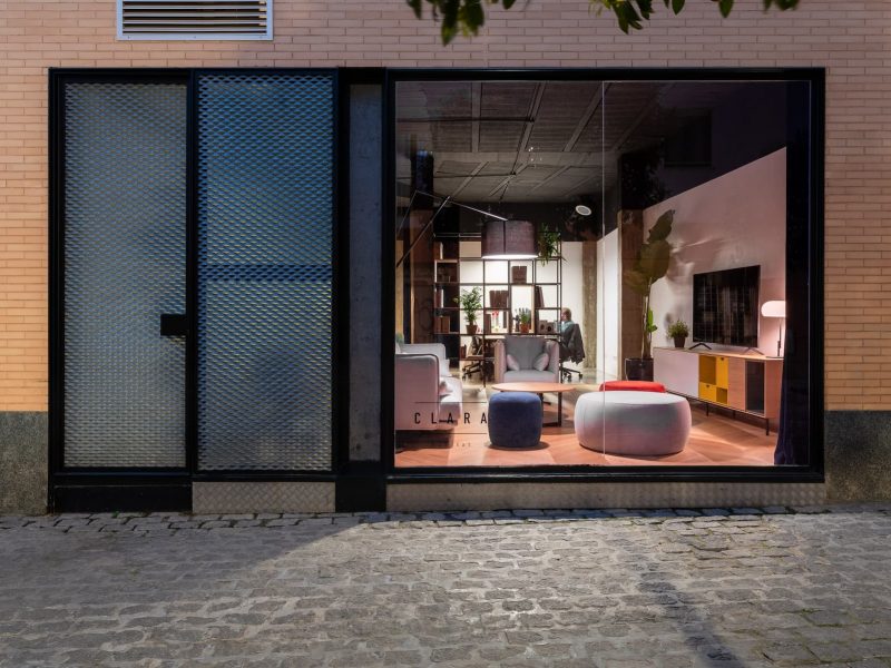 Escaparate iluminado de la oficina desde la calle adoquinada, con fachada de ladrillo
