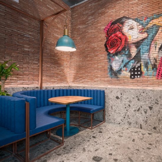 Fachada con rótulo y alicatado verde de la pizzería Piazza di Pezzi