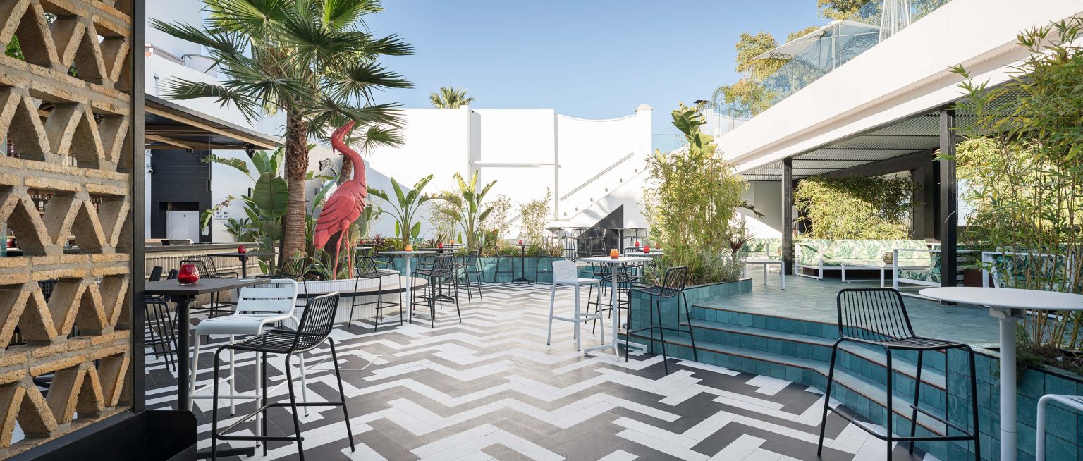Terraza con palmeras, celosía de madera y suelo de espiga en blanco y negro, en Terraza Lantana