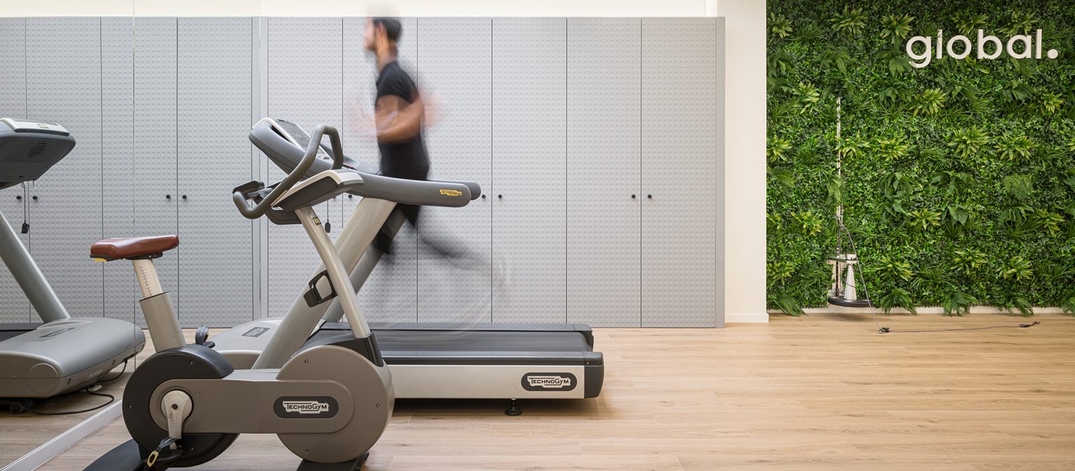 Sala de fitness con cinta de correr y bicicleta ante el jardín vertical