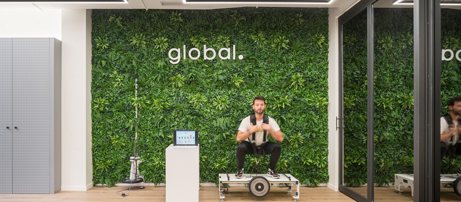 Jardín vertical con el rótulo global y un hombre entrenando en una plataforma