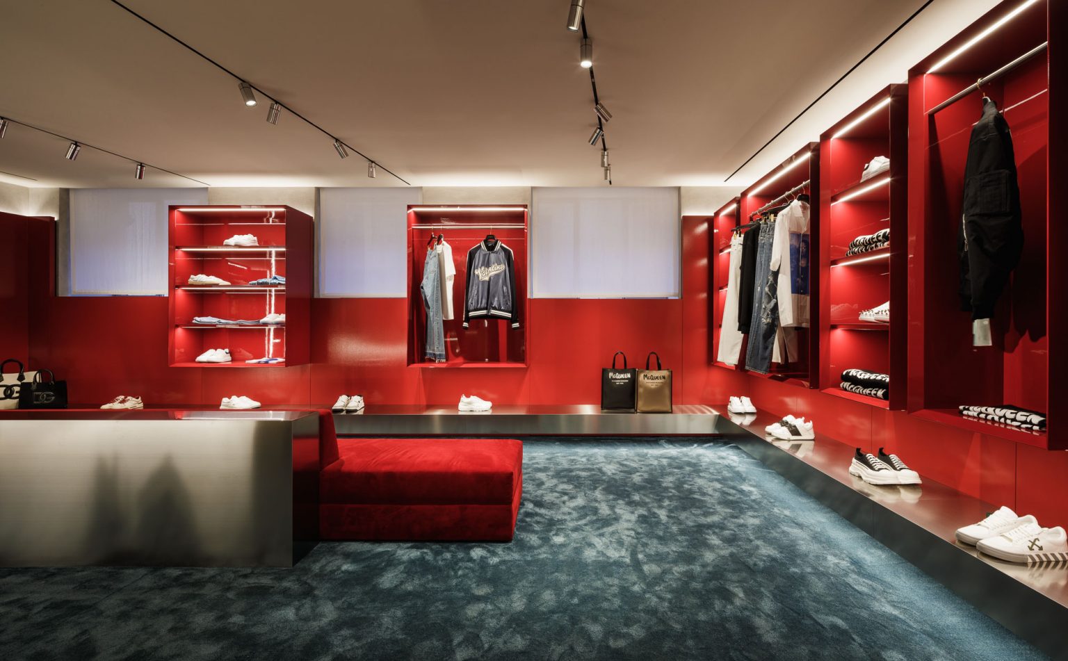 Tienda de ropa con módulos rojos retroiluminados y moqueta azul