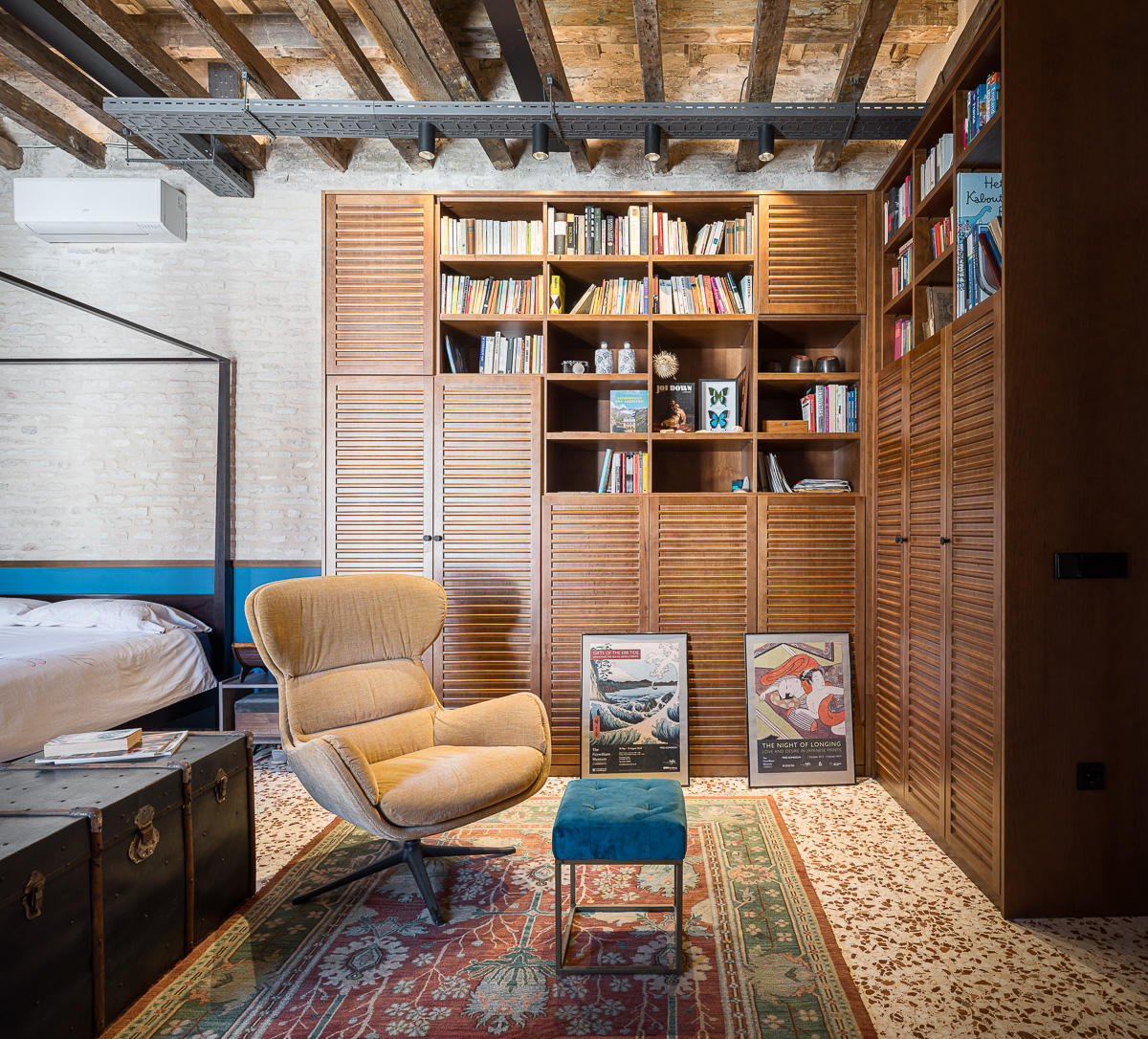 Dormitorio con librería de madera y techo de vigas en la vivienda de Conde Torrejón