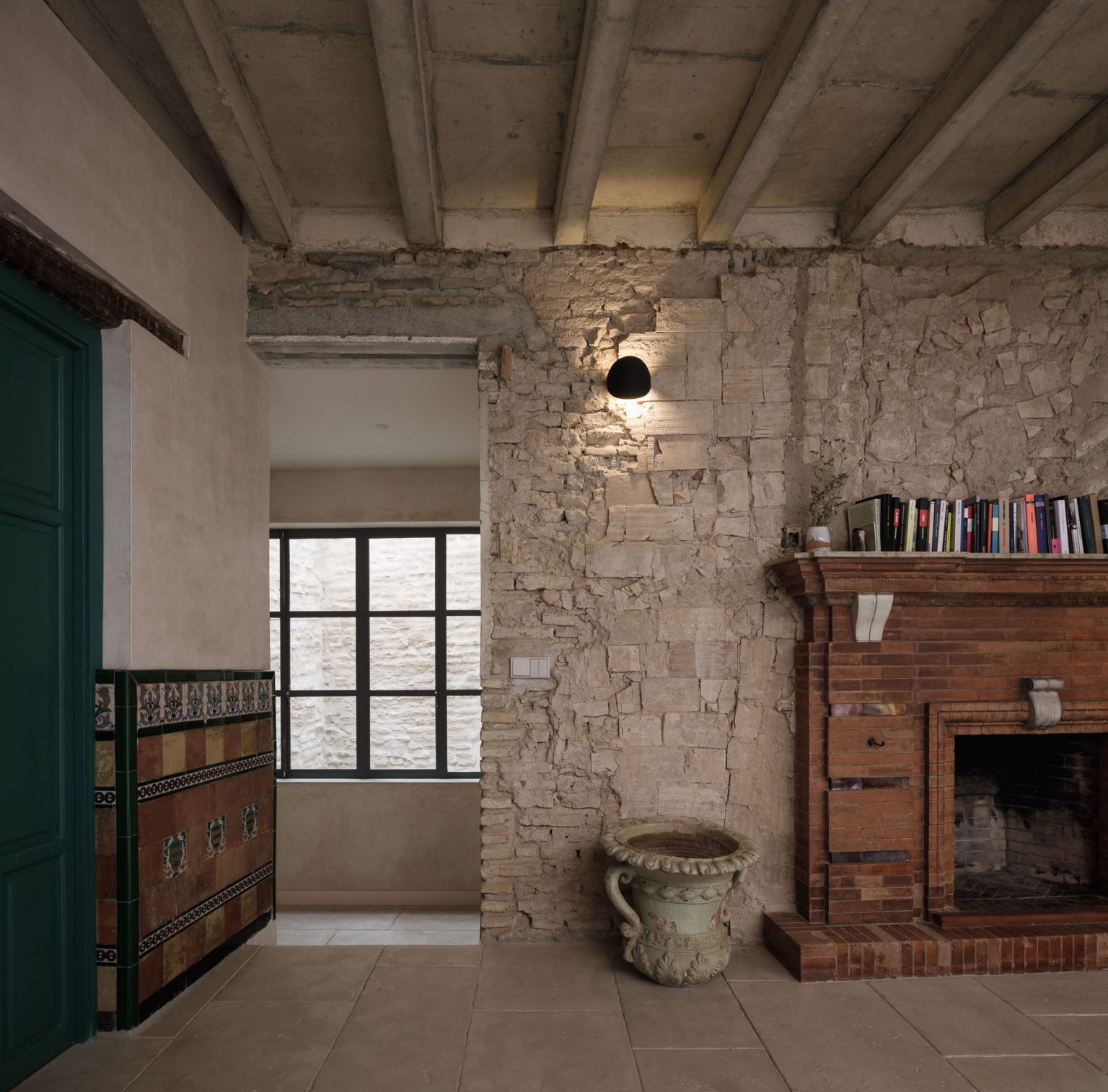 Estancia con muro de piedra vista, techo de vigas, chimenea de ladrillo y puerta verde